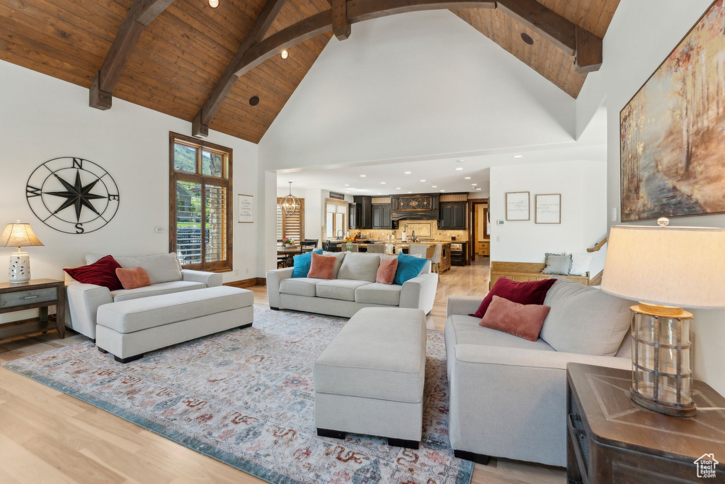 Living area featuring light wood-style flooring, wood ceiling with exposed beams, a chandelier, high vaulted ceiling, and recessed lighting