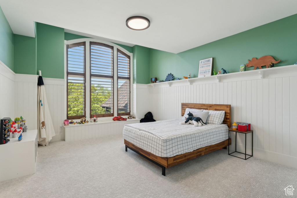 Carpeted bedroom featuring a wainscoted wall and a decorative wall