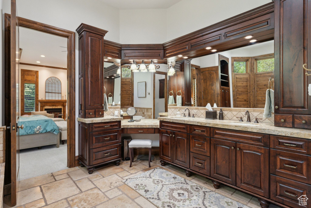 Bathroom with ensuite bath, decorative backsplash, double vanity, crown molding, and stone tile floors