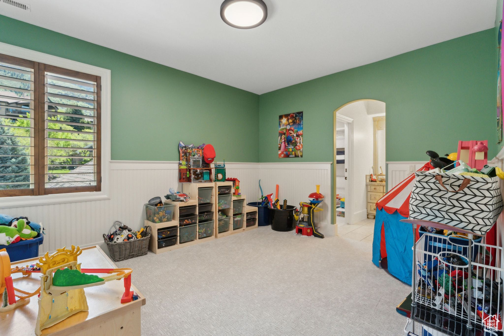 Playroom with arched walkways, wainscoting, and carpet floors