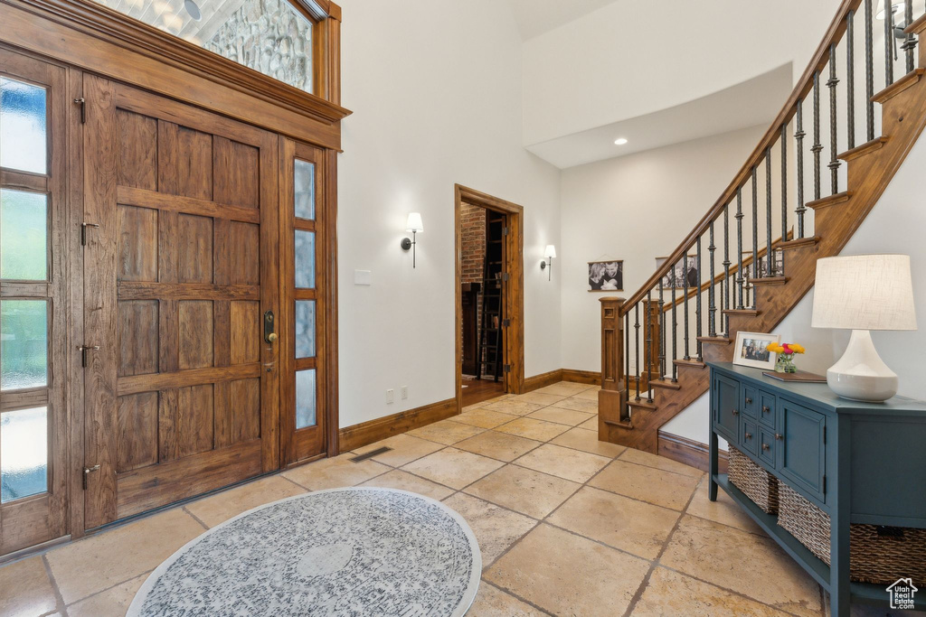 Foyer entrance featuring baseboards, stairway, a towering ceiling, and healthy amount of natural light