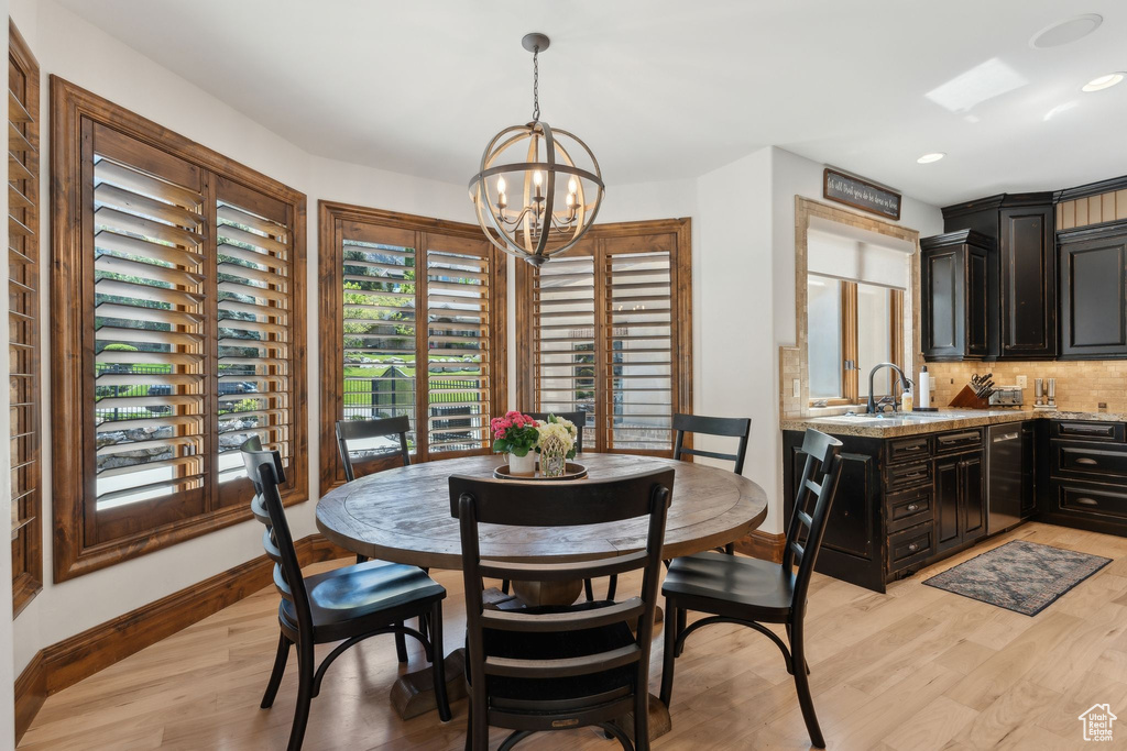 Dining area with a chandelier, baseboards, light wood finished floors, and recessed lighting