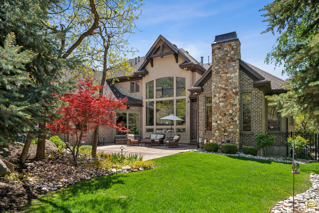 Back of property featuring a patio area, a chimney, brick siding, and stucco siding