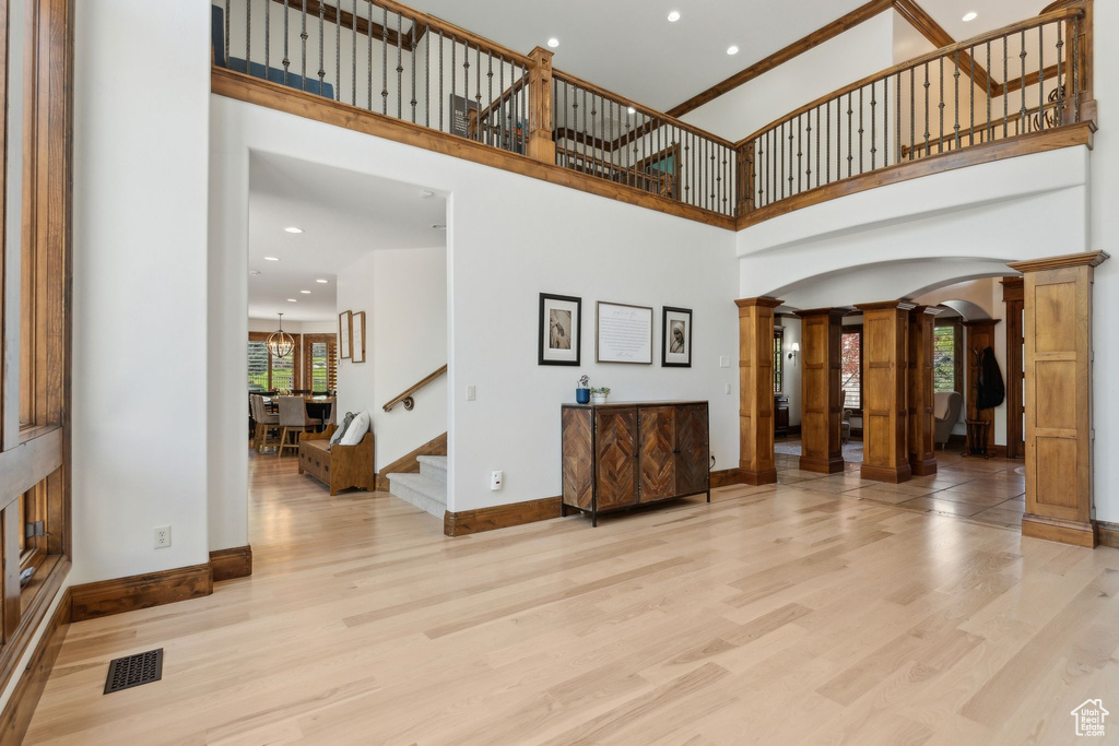 Unfurnished living room featuring decorative columns, arched walkways, wood finished floors, stairway, and baseboards