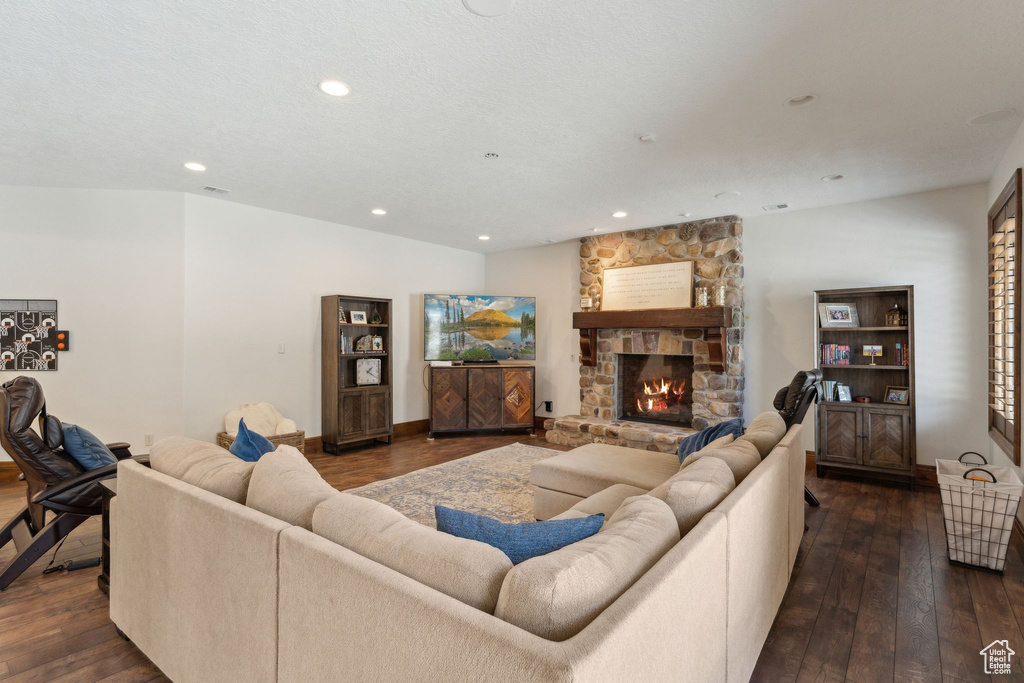 Living area with dark wood-type flooring, recessed lighting, a fireplace, and baseboards
