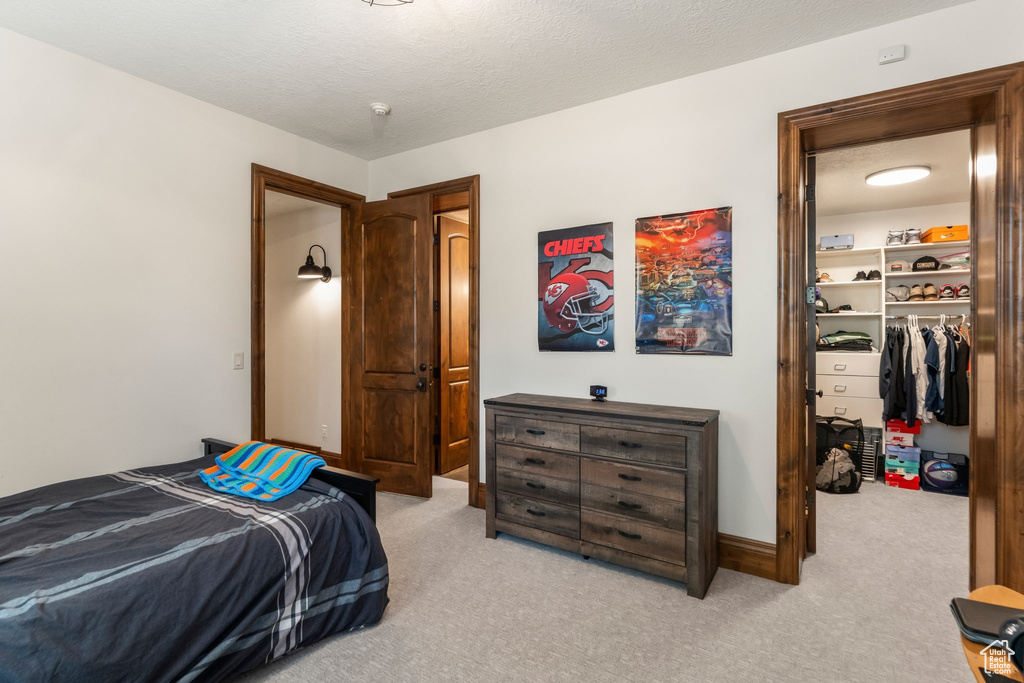Carpeted bedroom with a spacious closet and a closet