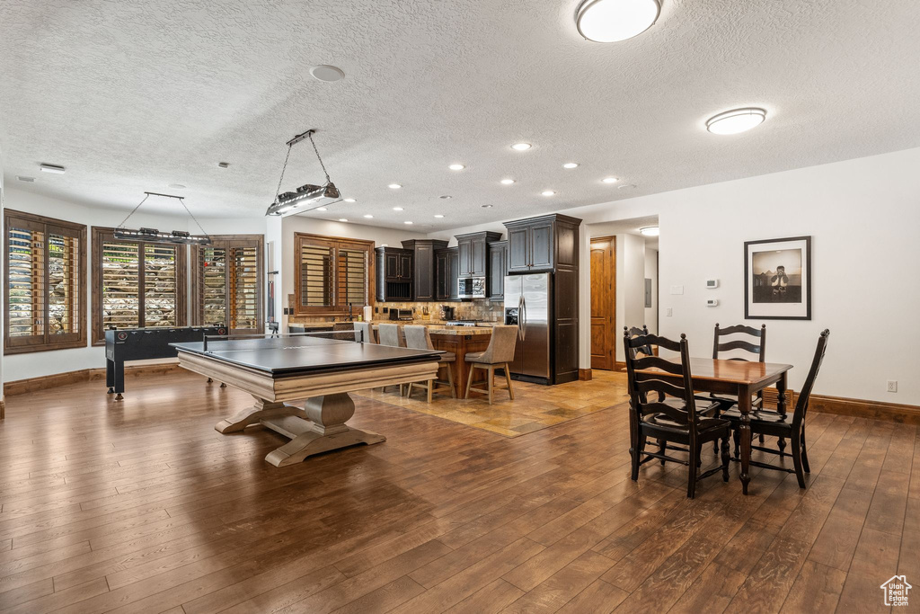 Game room featuring a textured ceiling, baseboards, dark wood-style floors, and recessed lighting