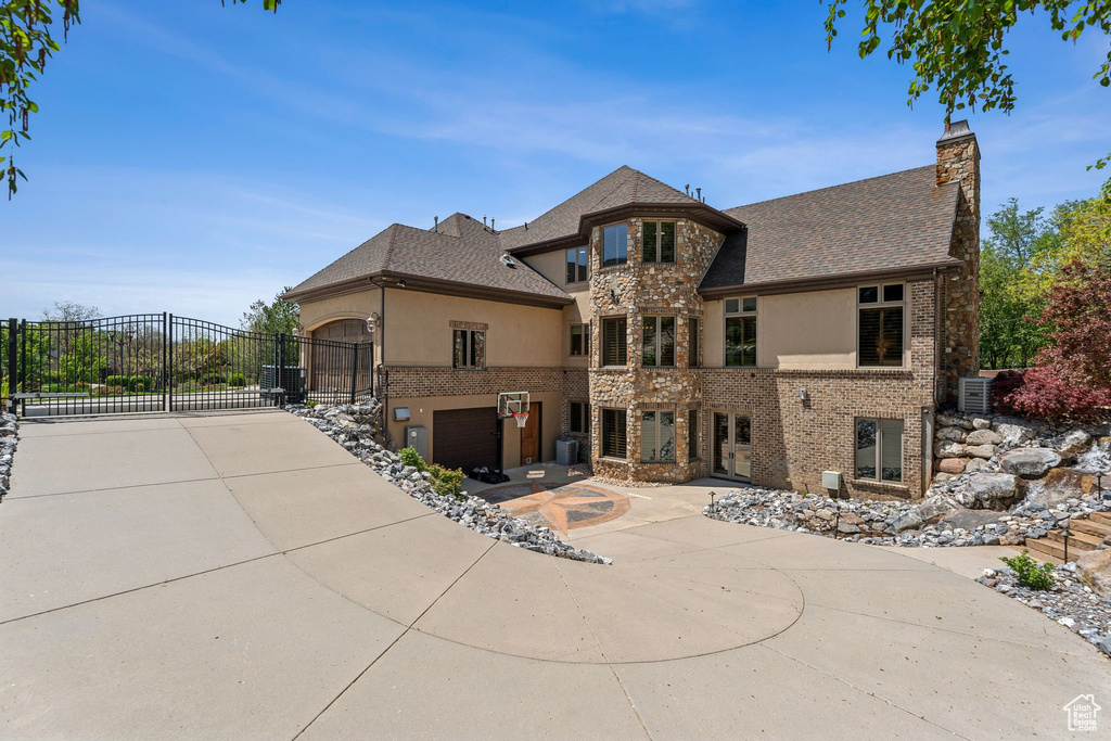 View of front of house with stucco siding, a gate, a chimney, and brick siding