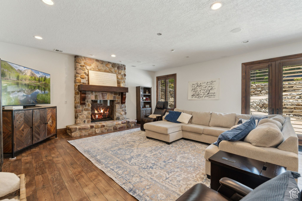 Living room with a textured ceiling, dark wood finished floors, recessed lighting, plenty of natural light, and a fireplace