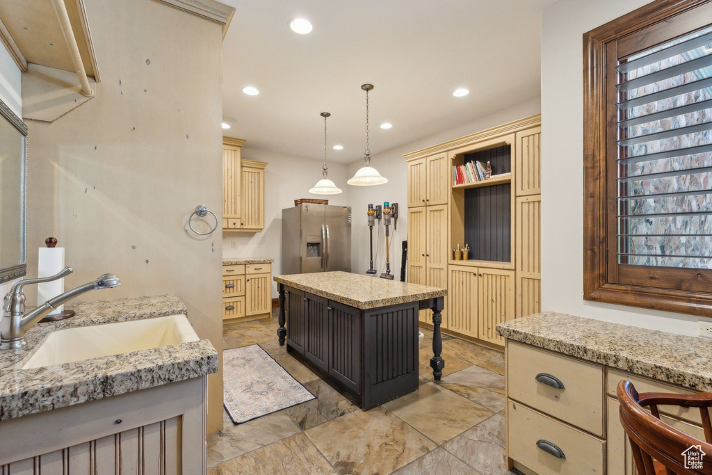Kitchen with stainless steel fridge with ice dispenser, a sink, recessed lighting, cream cabinets, and decorative light fixtures
