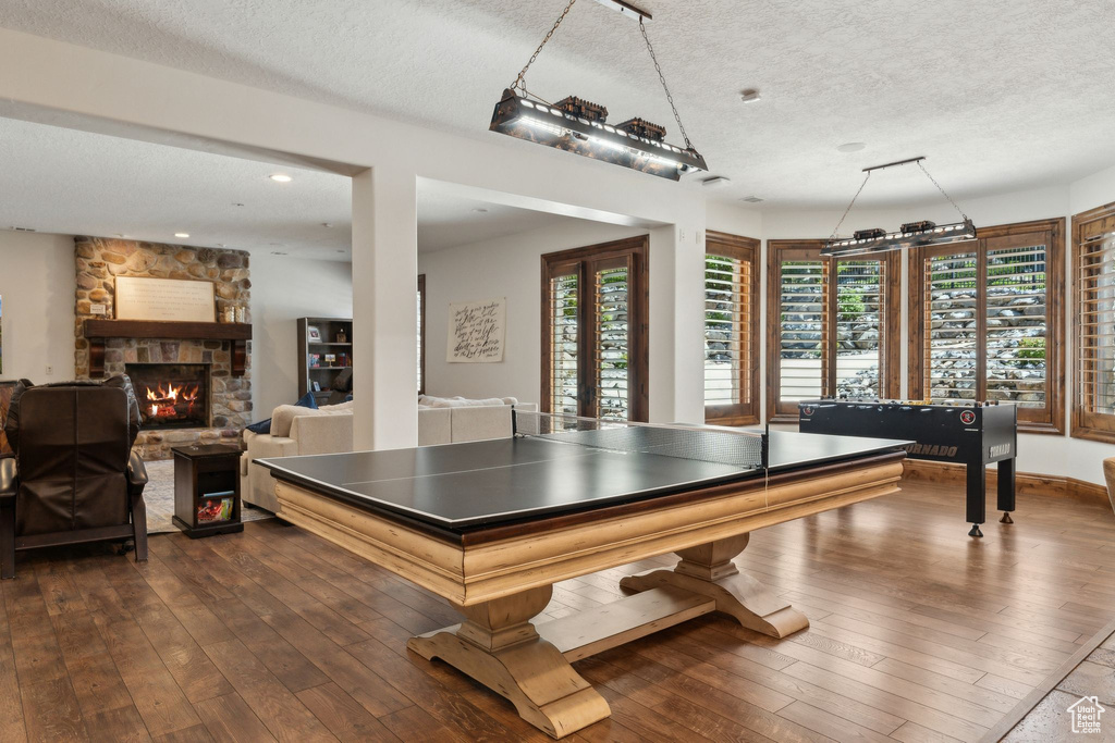 Rec room with a textured ceiling, dark wood-style flooring, healthy amount of natural light, a fireplace, and recessed lighting
