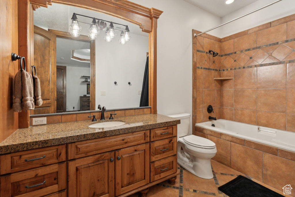 Bathroom featuring tile patterned floors, toilet, tiled shower / bath, and vanity