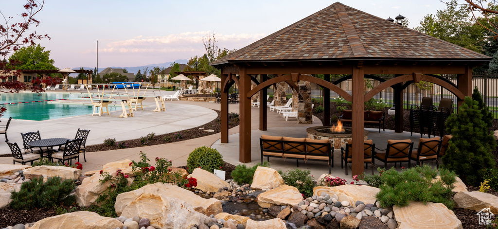 View of community featuring a gazebo, a swimming pool, an outdoor fire pit, a patio area, and a mountain view