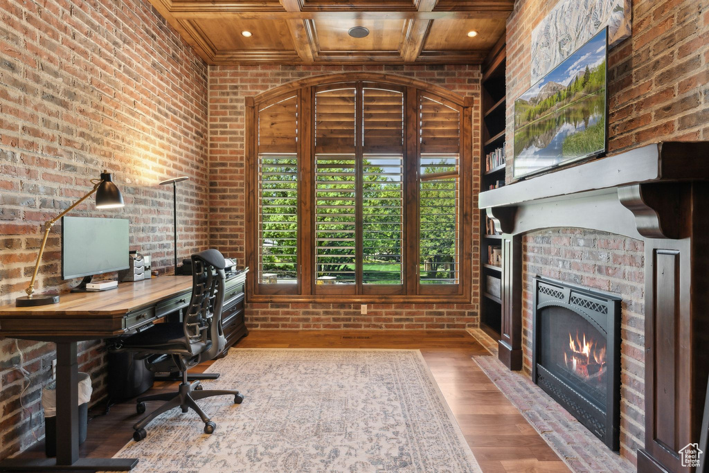 Office space with brick wall, wood finished floors, a fireplace, coffered ceiling, and wooden ceiling with exposed beams