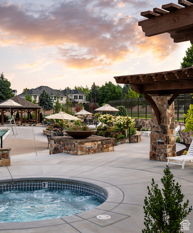 Pool at dusk with a gazebo, a patio, and a hot tub