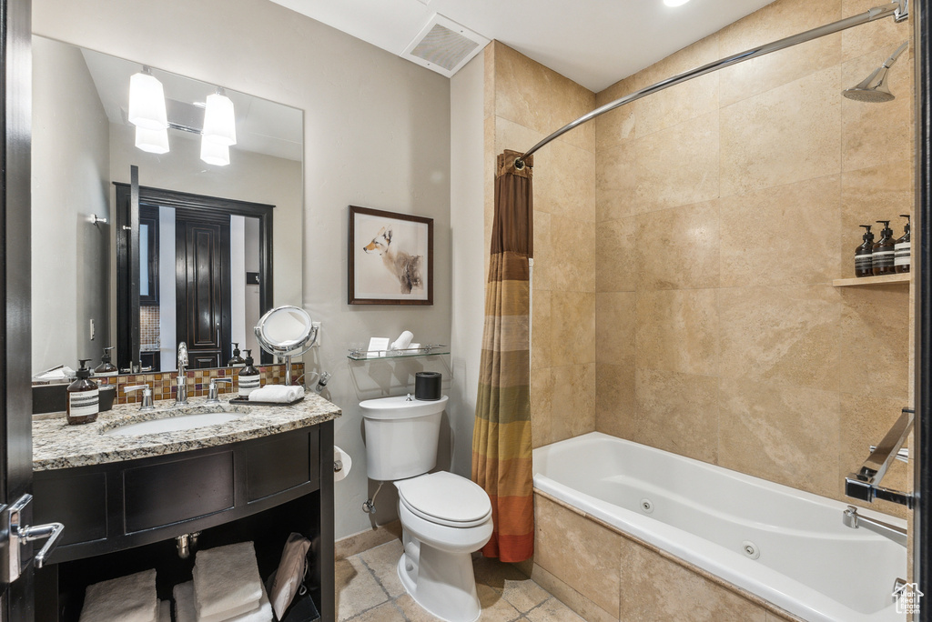 Full bathroom featuring a combined bath / shower with jetted tub, toilet, vanity, and tile patterned floors