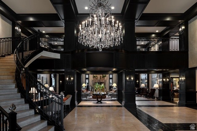 Lobby with a towering ceiling, stairway, coffered ceiling, and a decorative wall
