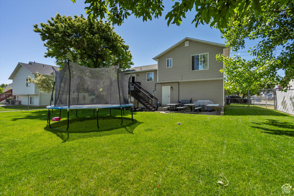 Rear view of property with a trampoline, stairs, and a patio area