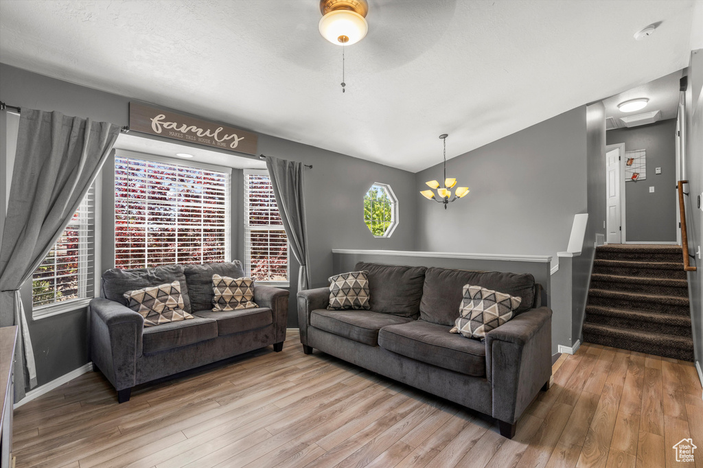Living area featuring wood finished floors, baseboards, healthy amount of natural light, and vaulted ceiling