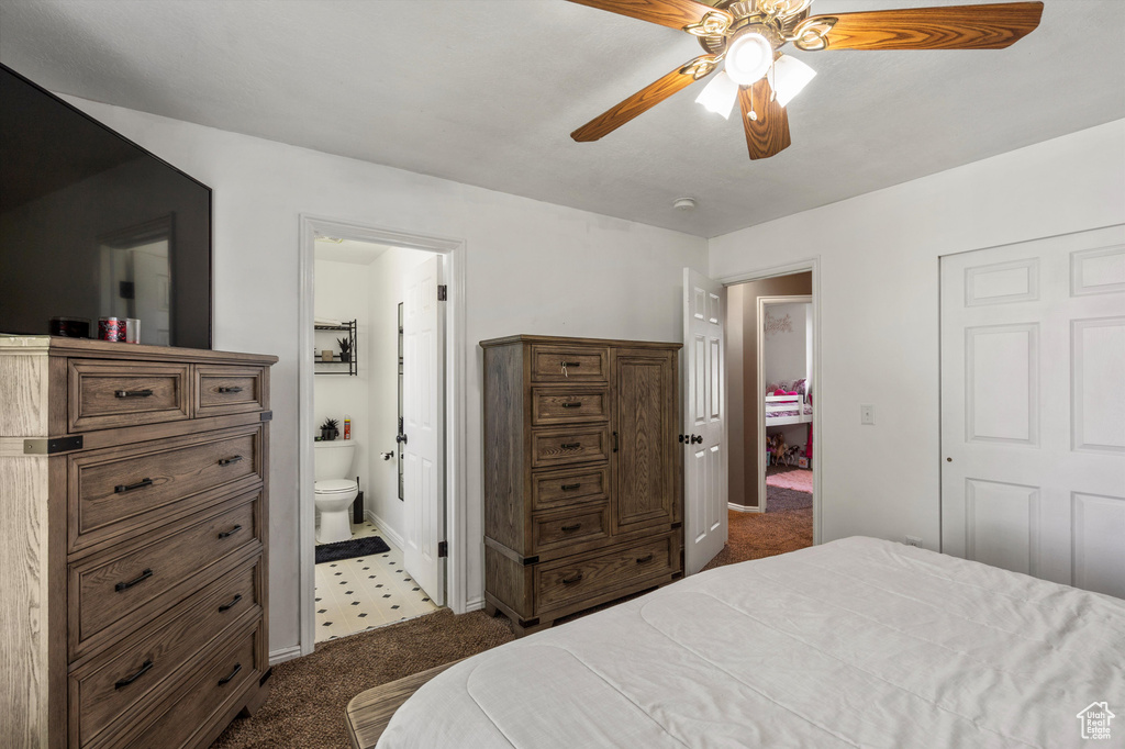 Bedroom with dark colored carpet, connected bathroom, baseboards, and a ceiling fan