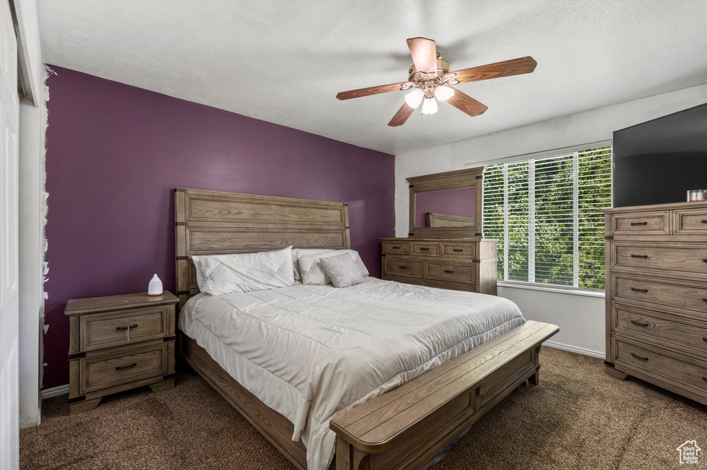 Bedroom with dark colored carpet, a ceiling fan, and baseboards