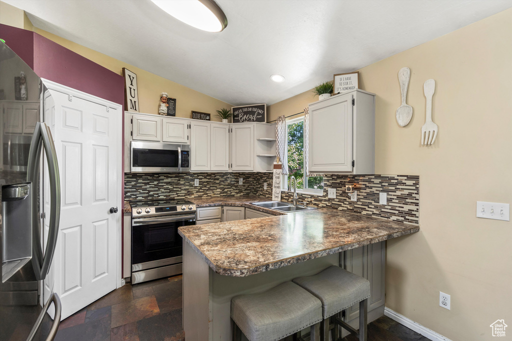 Kitchen with stainless steel appliances, a sink, a peninsula, tasteful backsplash, and recessed lighting