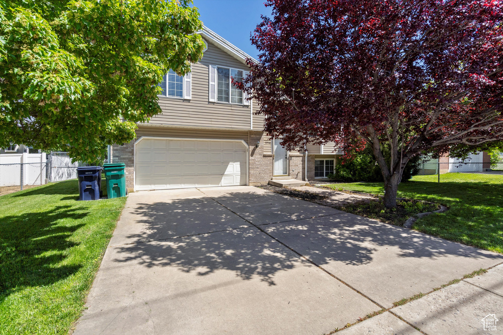 Obstructed view of property featuring a garage, driveway, and brick siding