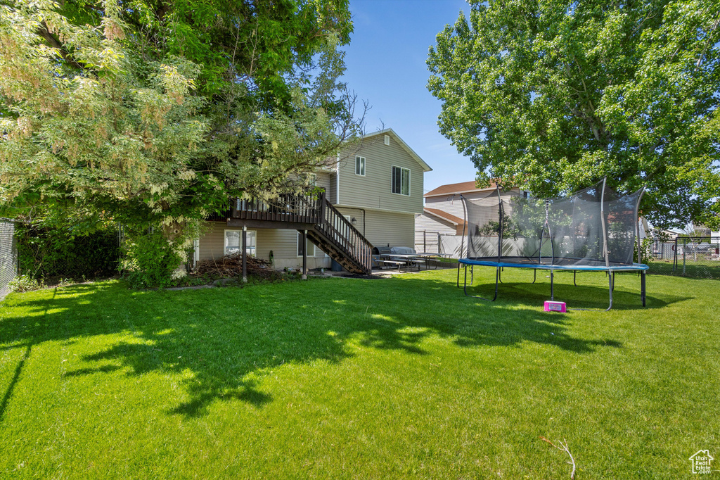 View of yard with a trampoline, stairs, and a wooden deck