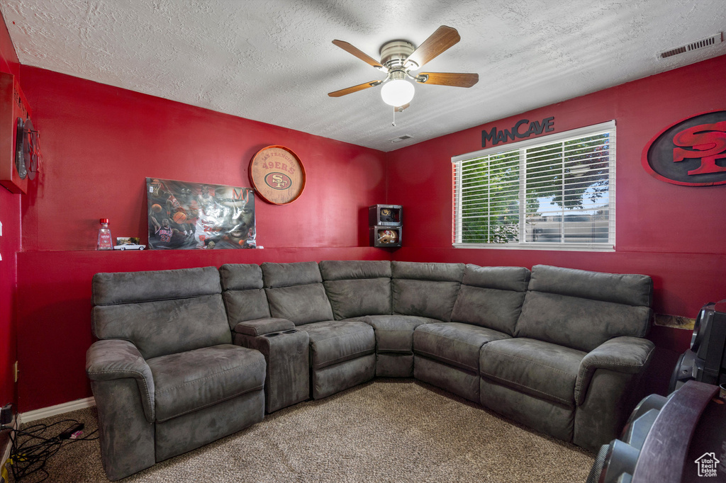 Carpeted living area with ceiling fan and a textured ceiling