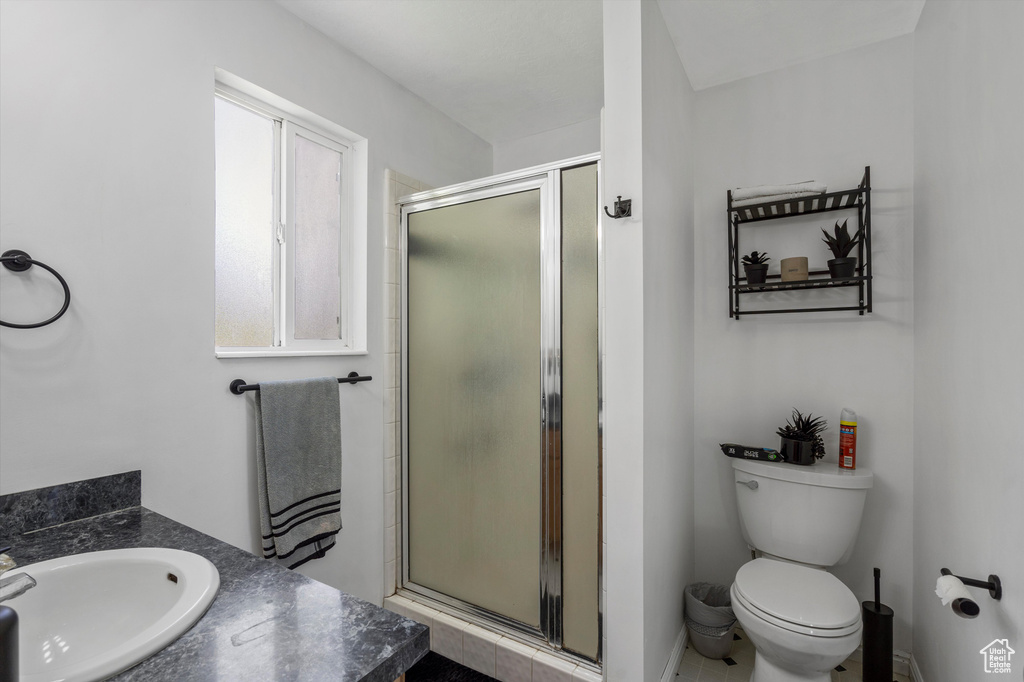 Full bathroom featuring a shower stall, vanity, toilet, and baseboards
