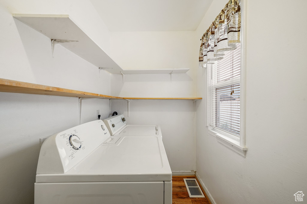 Laundry area featuring separate washer and dryer, dark wood-type flooring, and baseboards