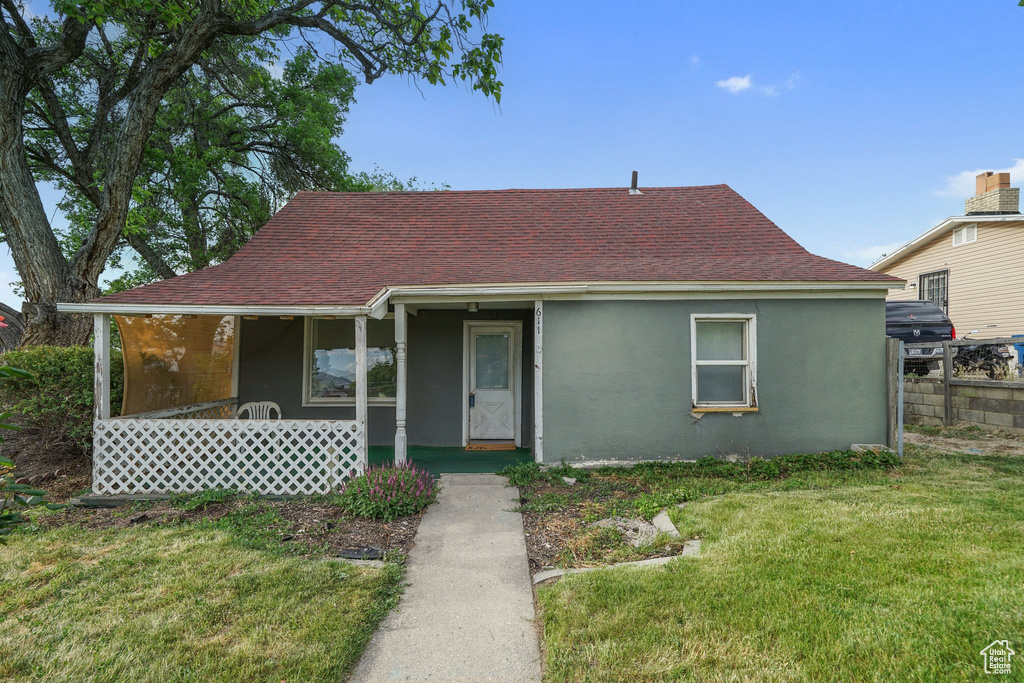 View of front of home with stucco siding, covered porch, and roof with shingles