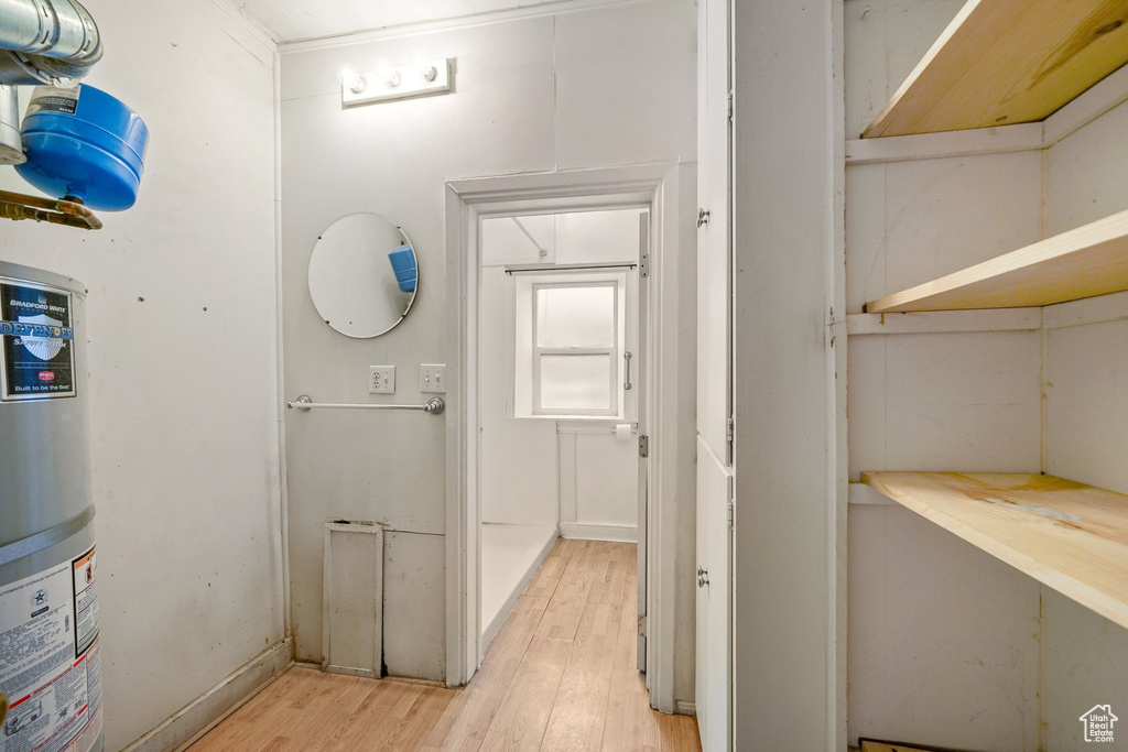 Hallway with water heater and light wood-style flooring