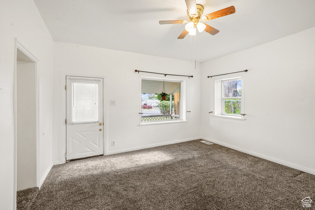 Carpeted empty room with a ceiling fan and baseboards