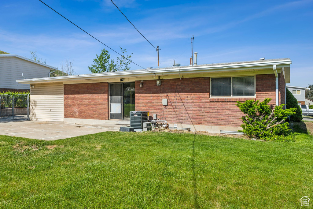 Back of house with a patio, a yard, brick siding, and central AC