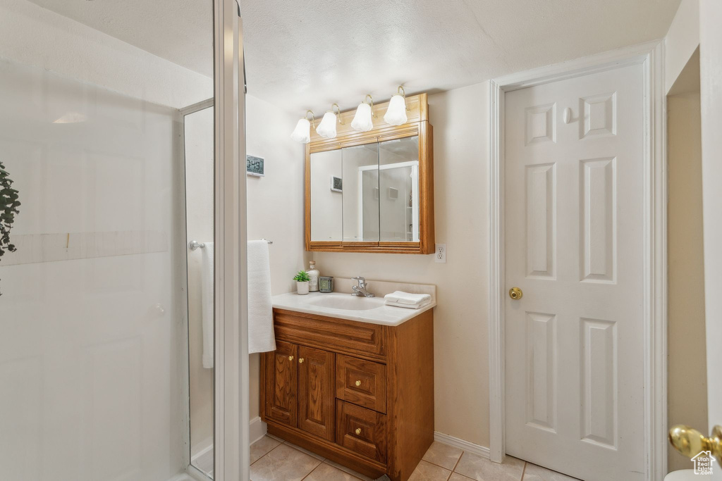 Full bathroom with vanity, a stall shower, tile patterned floors, and baseboards