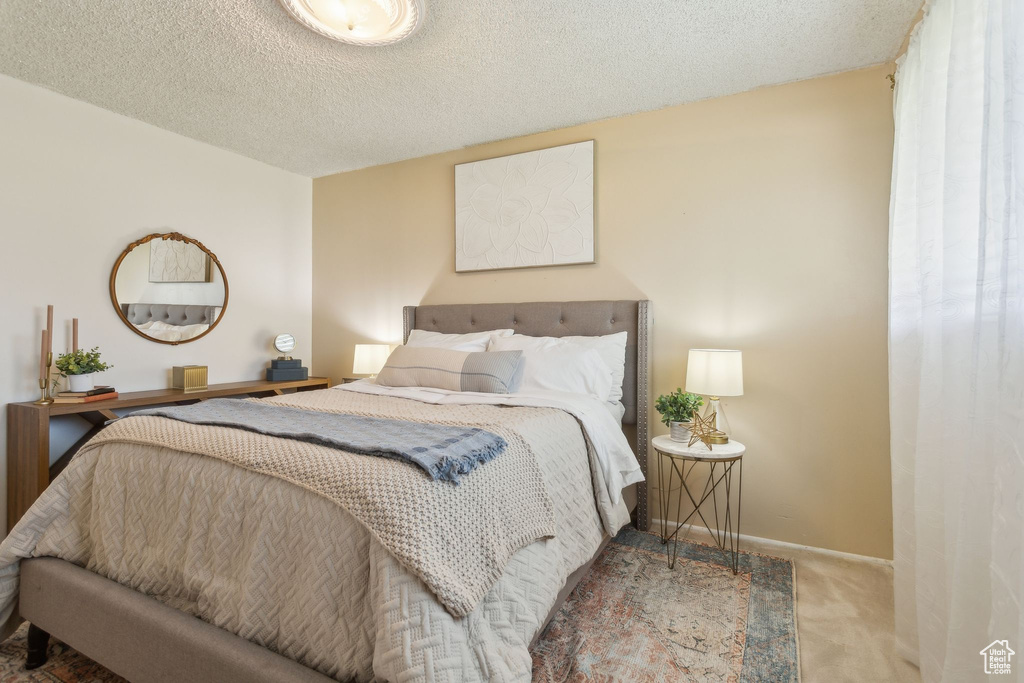 Bedroom with carpet, baseboards, and a textured ceiling