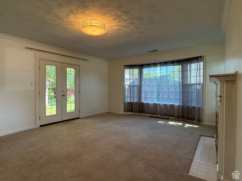 Unfurnished room with healthy amount of natural light, baseboards, french doors, carpet, and ornamental molding