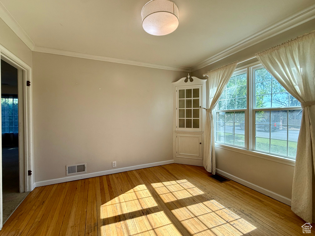 Unfurnished room featuring light wood-style flooring, baseboards, and crown molding