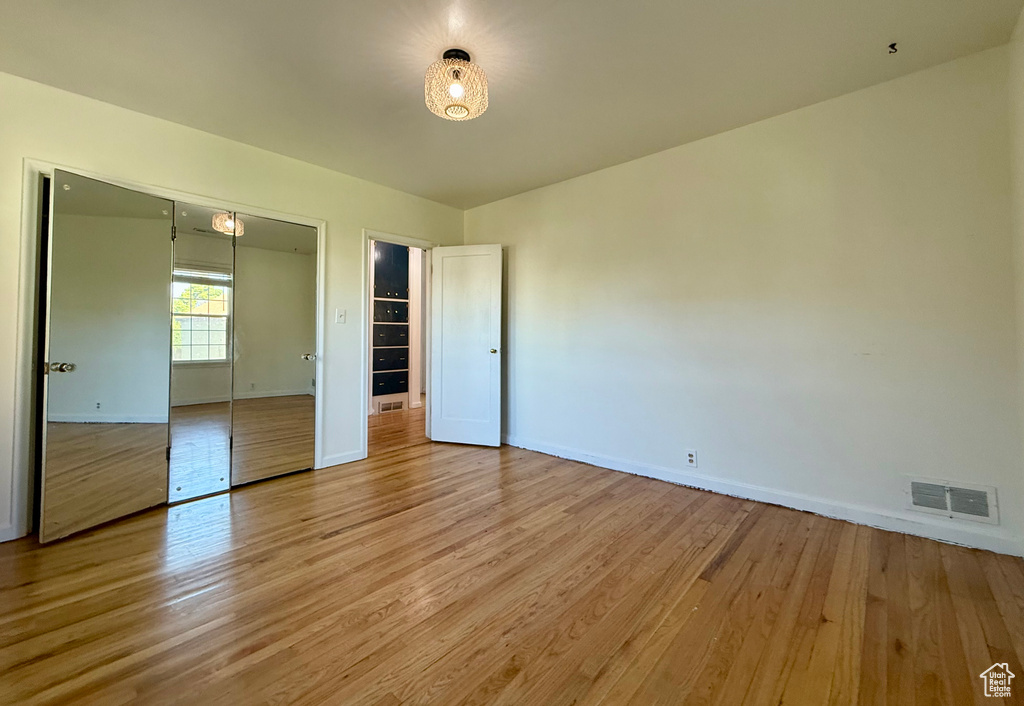 Unfurnished bedroom with light wood-style floors, baseboards, and a closet