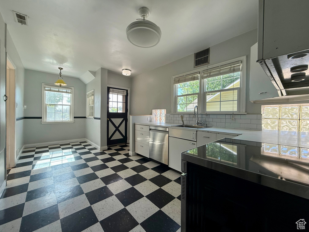 Kitchen featuring dishwasher, a sink, light floors, light countertops, and backsplash