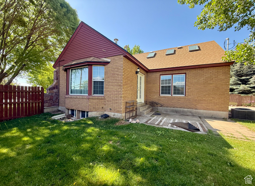 Back of property featuring entry steps, central AC, a patio, brick siding, and roof with shingles