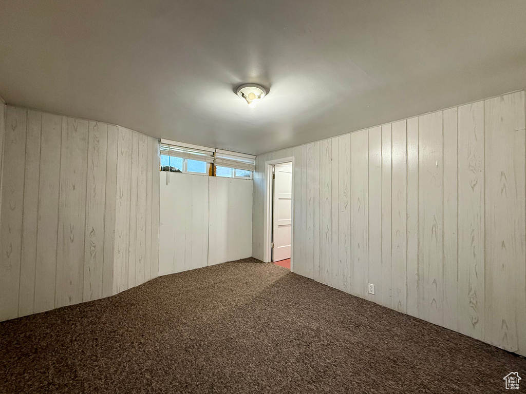 Unfurnished room featuring wooden walls and carpet