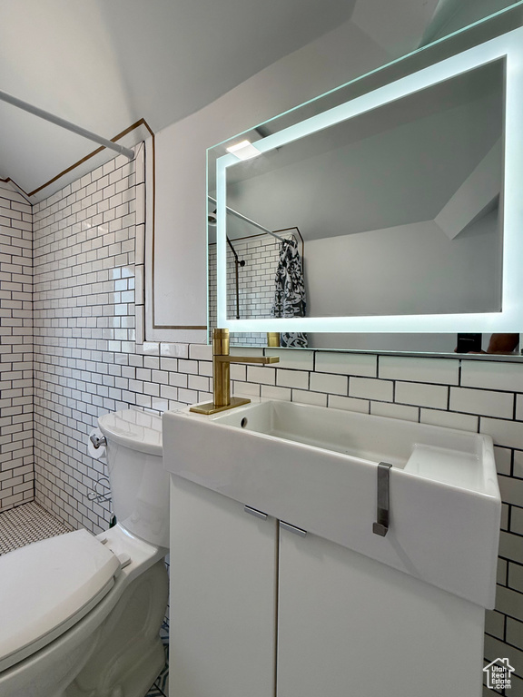 Bathroom featuring tile walls, a tile shower, toilet, vanity, and decorative backsplash