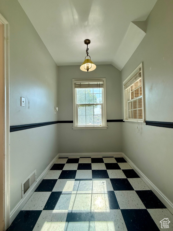 Unfurnished room featuring tile patterned floors, baseboards, and vaulted ceiling