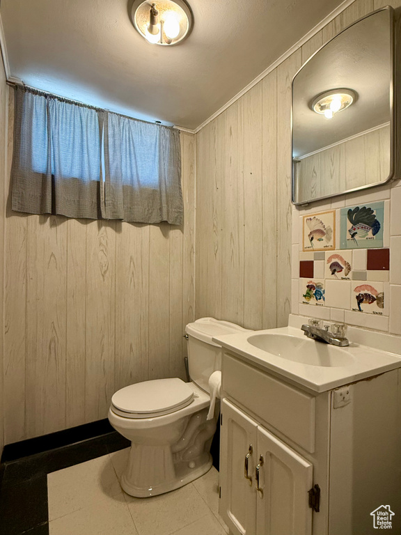Bathroom featuring vanity, tile patterned flooring, toilet, and wood walls