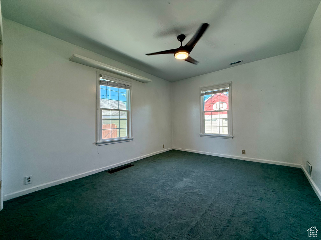 Spare room with plenty of natural light, baseboards, and dark colored carpet
