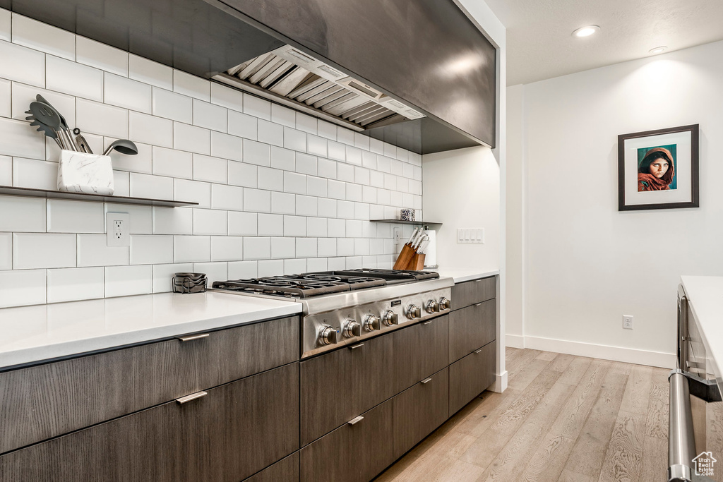 Kitchen with stainless steel gas stovetop, baseboards, light wood-type flooring, light countertops, and recessed lighting