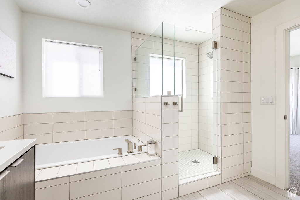 Bathroom featuring a shower stall, a bath, and vanity