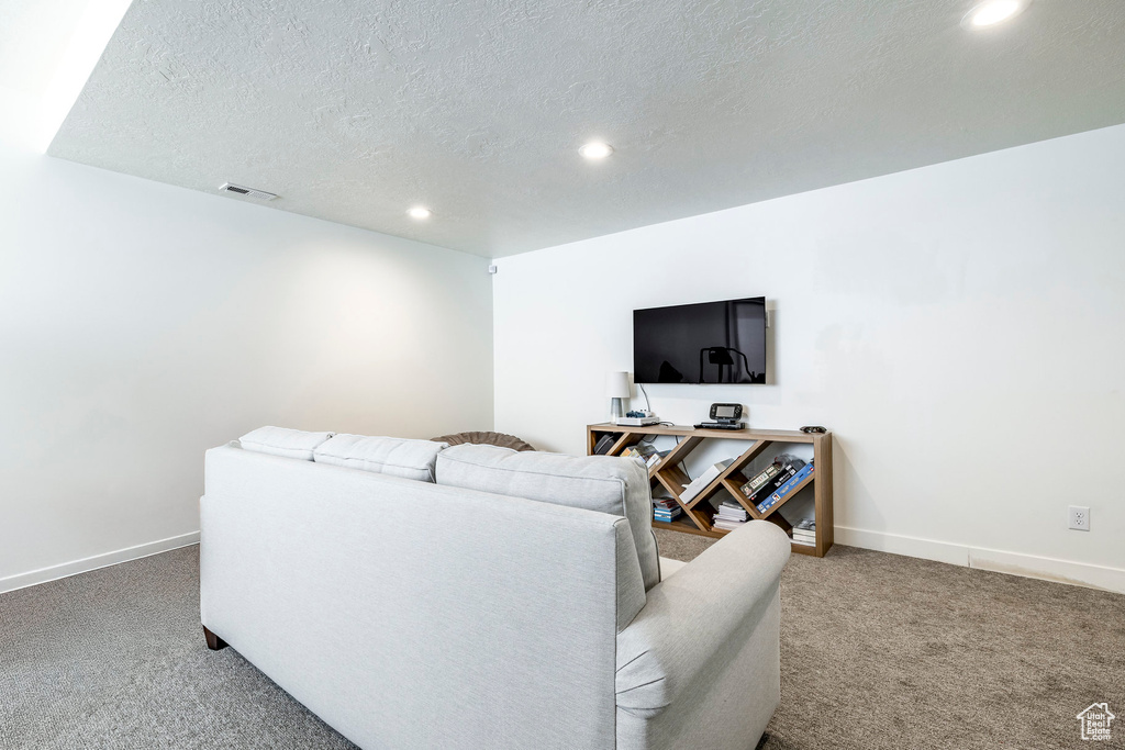 Carpeted living area with recessed lighting, a textured ceiling, and baseboards